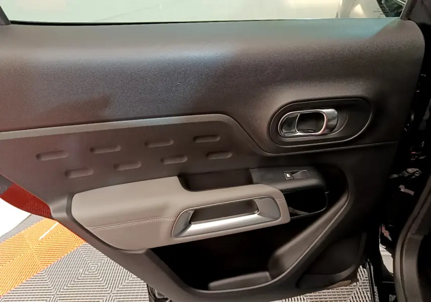 Vue rapprochée de la porte côté gauche noire et grise du Citroën C5 Aircross avec poignée argentée et commande de vitre.