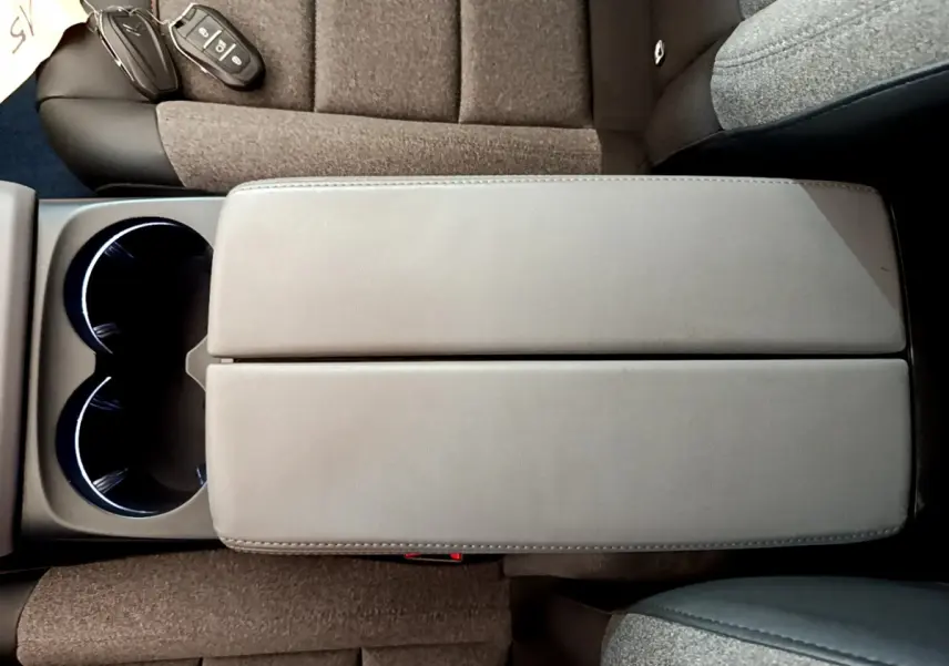 Vue plongeante sur l'accoudoir central gris et les sièges tissu marron du Citroën C5 Aircross 2020.