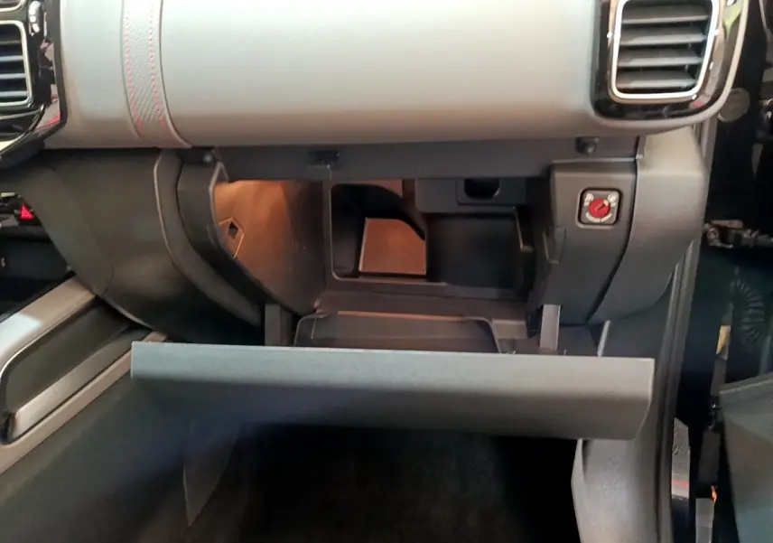 Ouverture de la boîte à gants côté passager du Citroën C5 Aircross noir, montrant le rangement intérieur et les finitions grises du tableau de bord.