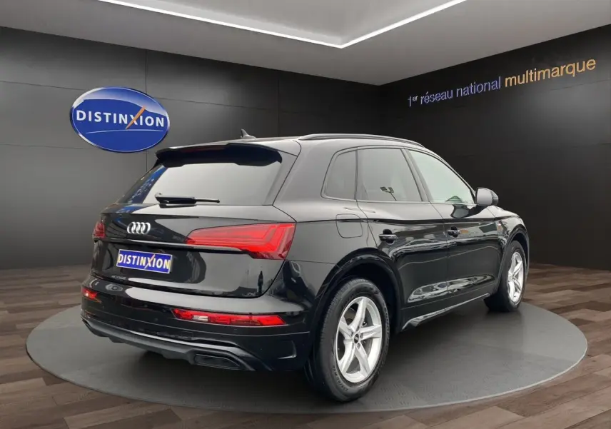 Audi Q5 noir vue 3/4 arrière droit, avec feux LED et jantes alliage cinq branches visibles en showroom.