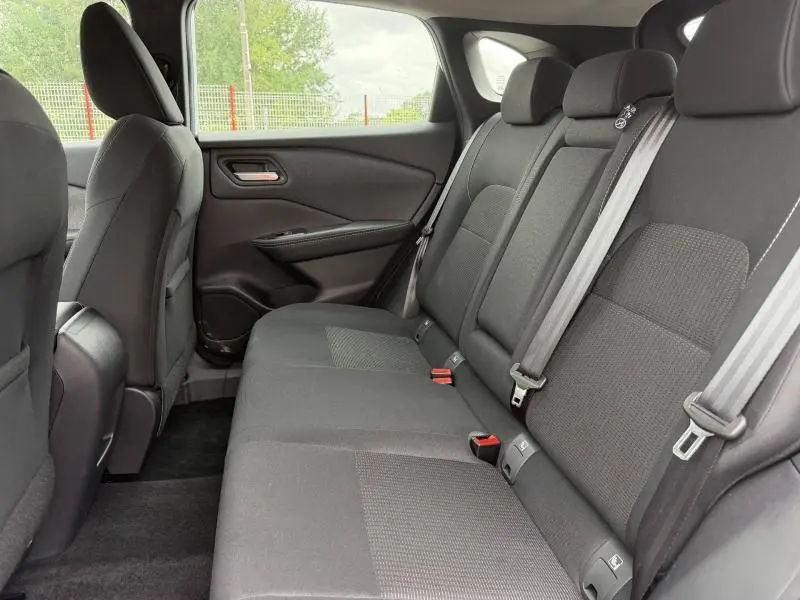 Vue intérieure côté droit de la banquette arrière noire du Nissan Qashqai 1.3 Mild Hybrid 2025, avec ceintures de sécurité visibles.