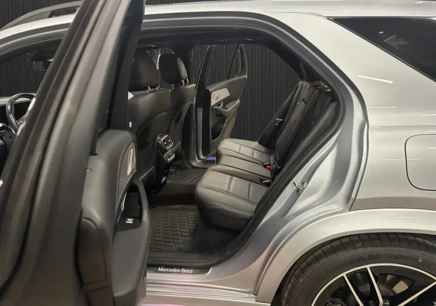 Vue côté droit arrière ouverte du Mercedes GLE 400 E Hybrid AMG Line 2023 argent métallisé, montrant les sièges arrière en cuir noir.