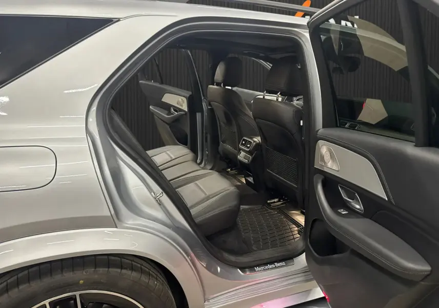 Vue côté gauche arrière du Mercedes GLE 400 E Hybrid AMG Line 2023 argent, portes ouvertes montrant l’intérieur cuir noir et les finitions haut de gamme.