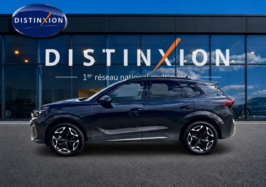 Vue latérale droite d'une CUPRA TERRAMAR 1.5 etsi hybrid gris Timanfaya avec jantes 19 pouces devant une vitrine Distinxion.