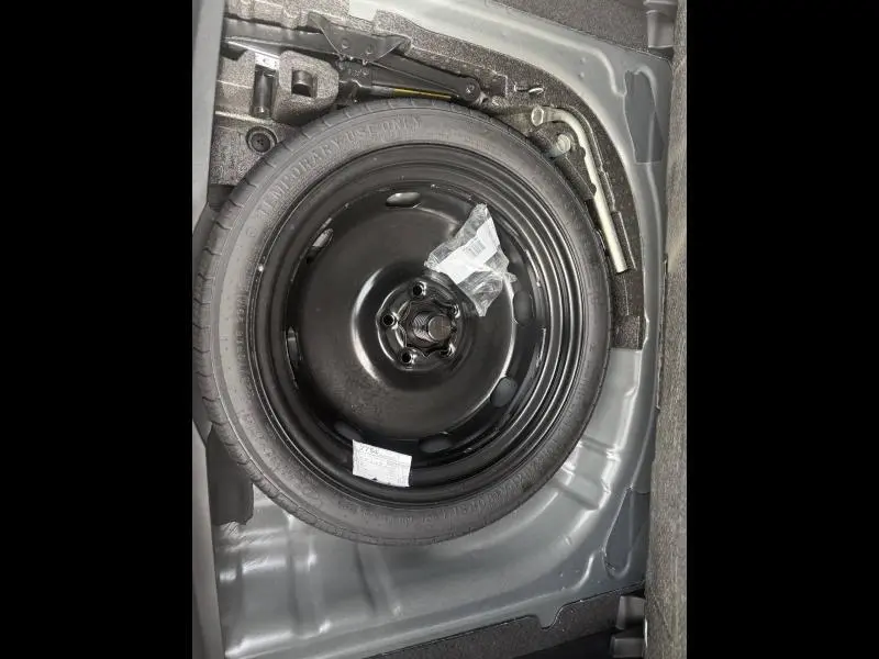 Roue de secours noire dans le coffre d'une CUPRA Formentor bleu, avec outils de changement visibles autour.
