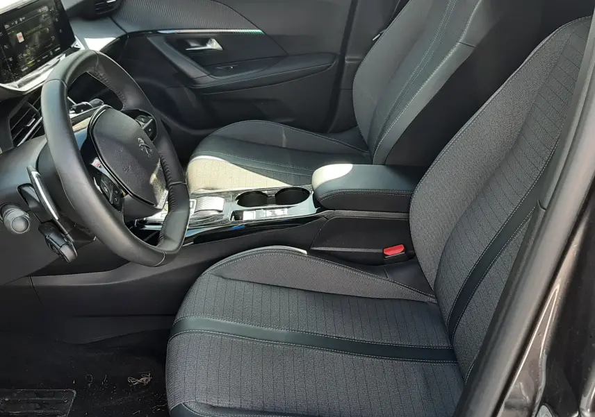 Intérieur avant droit du Peugeot 2008 gris platinium 2023, sièges tissu noir et console centrale brillante.