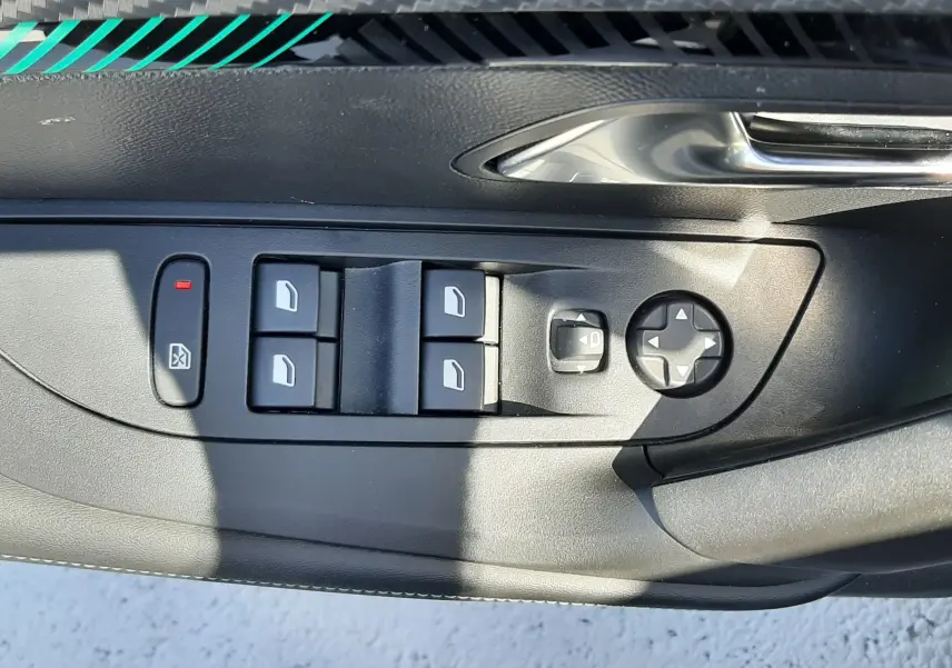 Gros plan sur les commandes des vitres et rétroviseurs côté gauche d'une Peugeot 2008 gris platinium 2023.
