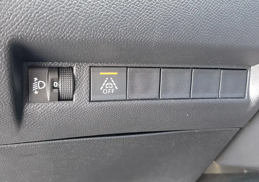 Gros plan sur les commandes noires du tableau de bord du Peugeot 2008 2023, avec bouton d'alerte de maintien de voie désactivé.