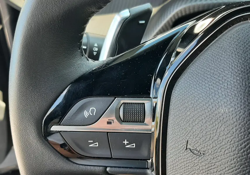 Gros plan sur la commande gauche du volant noir du Peugeot 2008 2023, avec boutons de volume et molette tactile.