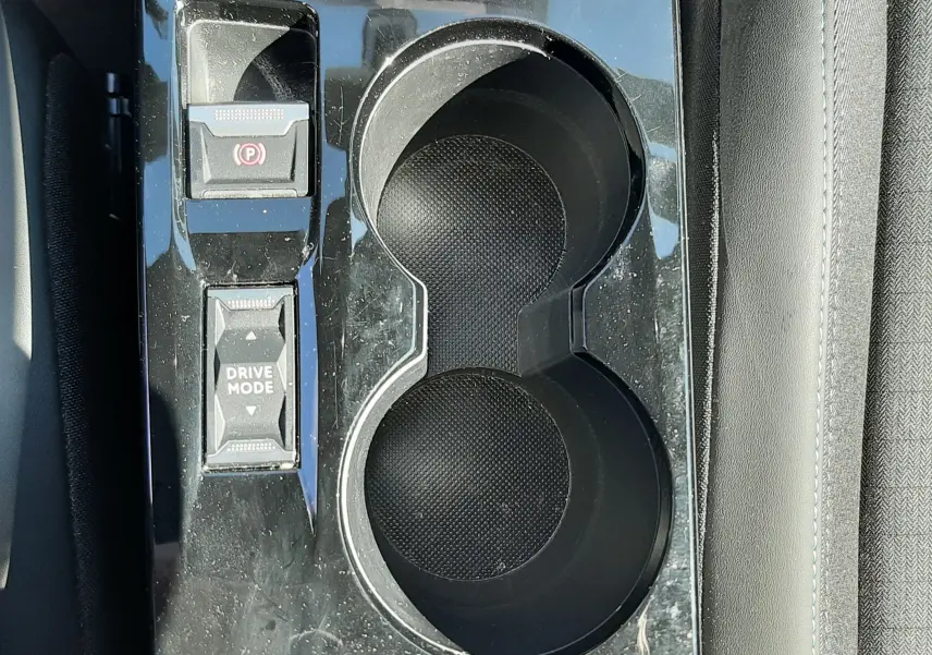 Vue plongeante sur la console centrale noire du Peugeot 2008 gris platinium avec porte-gobelets et commandes Drive Mode.