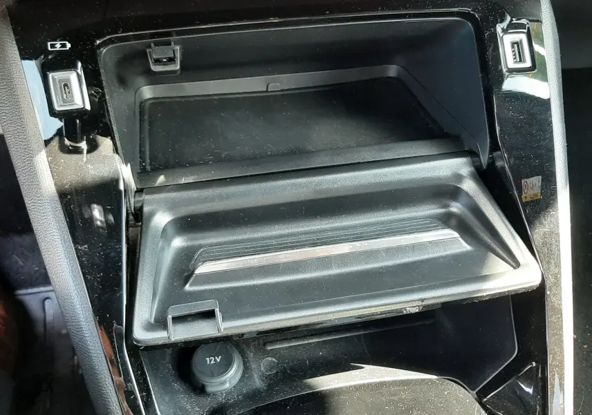 Gros plan sur la console centrale noire du Peugeot 2008 2023, montrant un compartiment ouvert et prises USB et 12V.