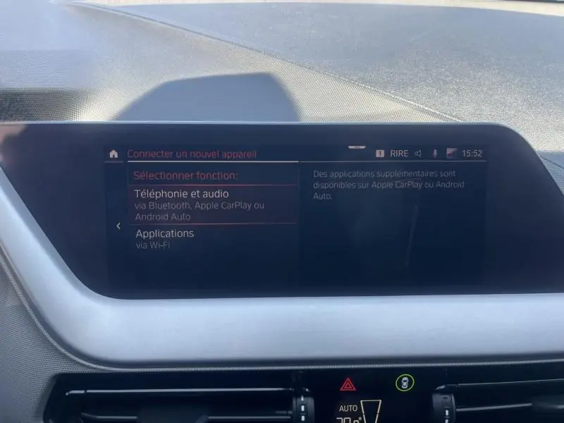Écran tactile central du tableau de bord de la BMW Série 1 noire, affichant les options de connexion smartphone.