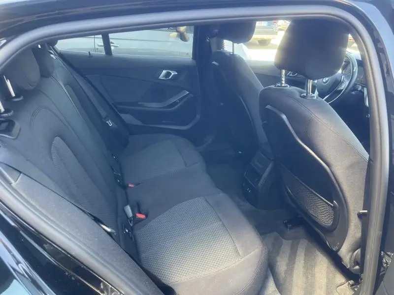 Intérieur arrière noir de la BMW Série 1 116dA 2020, vue côté gauche avec sièges tissu Grid Anthracite et portes ouvertes.