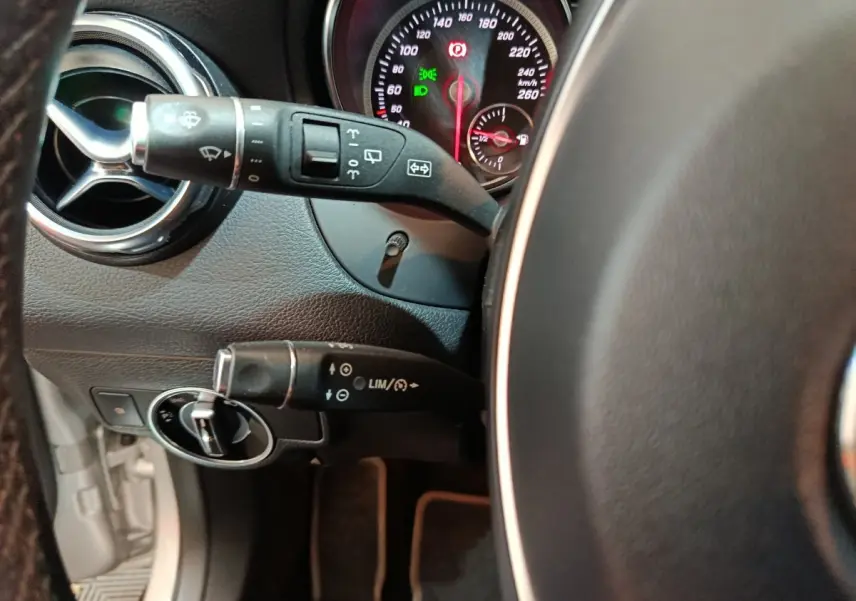 Gros plan sur le volant cuir et commandes au volant du Mercedes GLA 200 d Business Executive gris clair, tableau de bord visible.