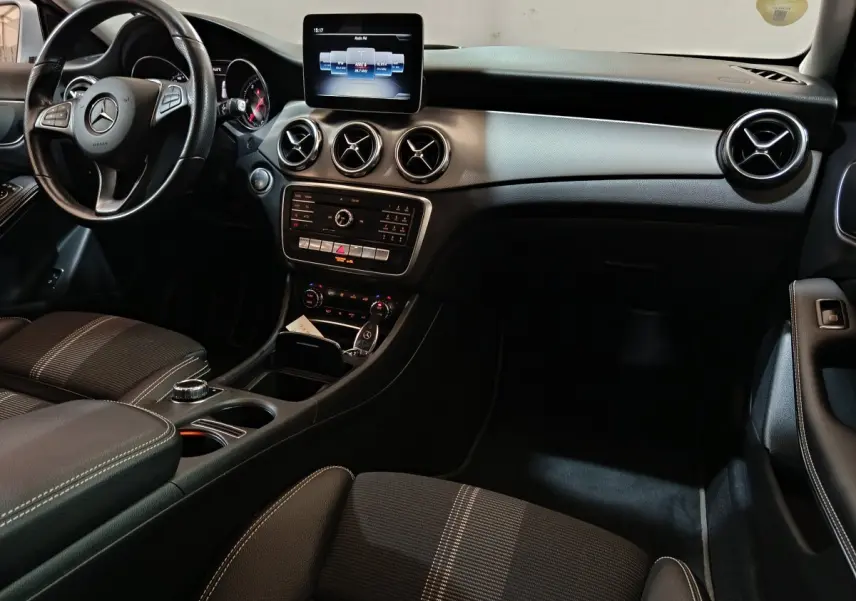 Intérieur noir du Mercedes GLA 200 d 2018, vue du tableau de bord avec écran central et volant multifonctions cuir.