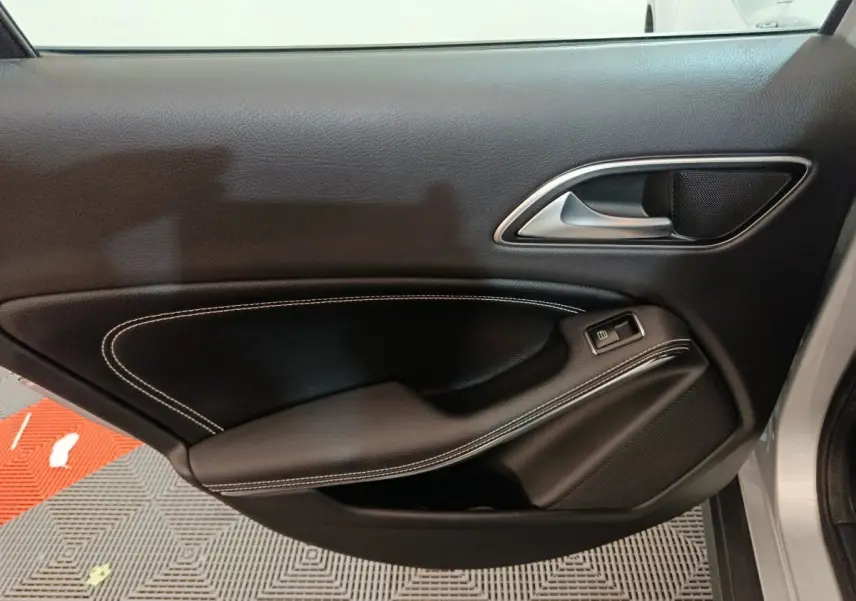 Gros plan sur la porte côté droit de la Mercedes GLA 200 d Business Executive gris clair, avec garniture noire et surpiqûres blanches.