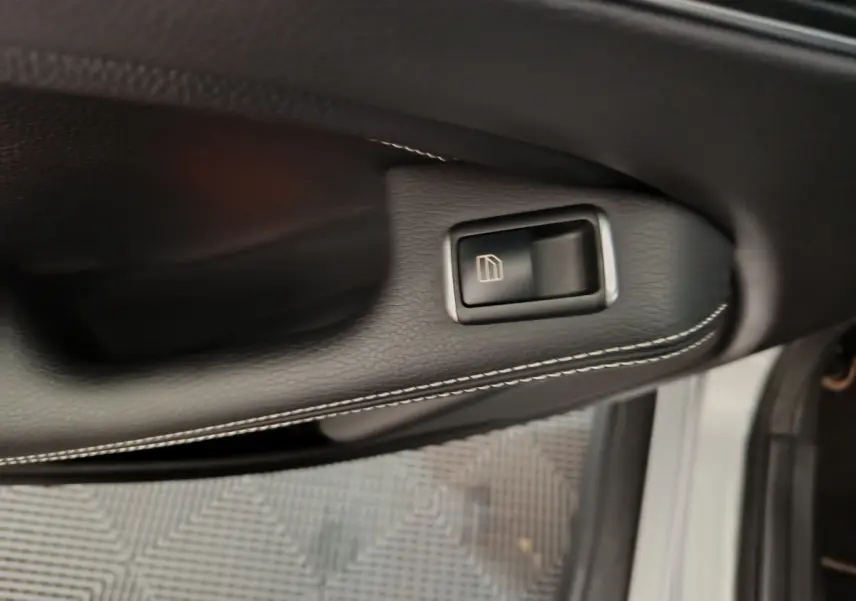 Bouton de commande de la vitre sur la porte côté conducteur d'un Mercedes GLA gris clair vu de près.