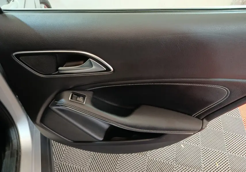 Gros plan sur la garniture intérieure noire avec surpiqûres blanches de la porte côté gauche d’un Mercedes GLA 200 d 2018.
