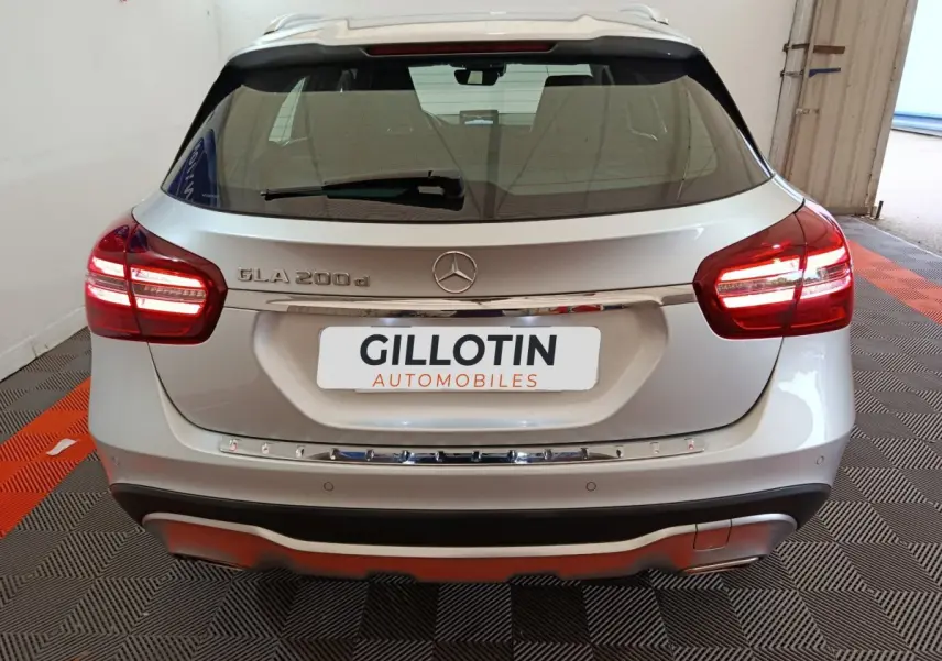 Vue arrière d'un Mercedes GLA 200 d gris clair avec feux LED et logo Mercedes visible sur un sol à damier noir et orange.