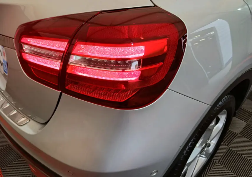 Gros plan sur le feu arrière droit allumé d'un Mercedes GLA 200 d Business Executive gris clair, avec jante visible.