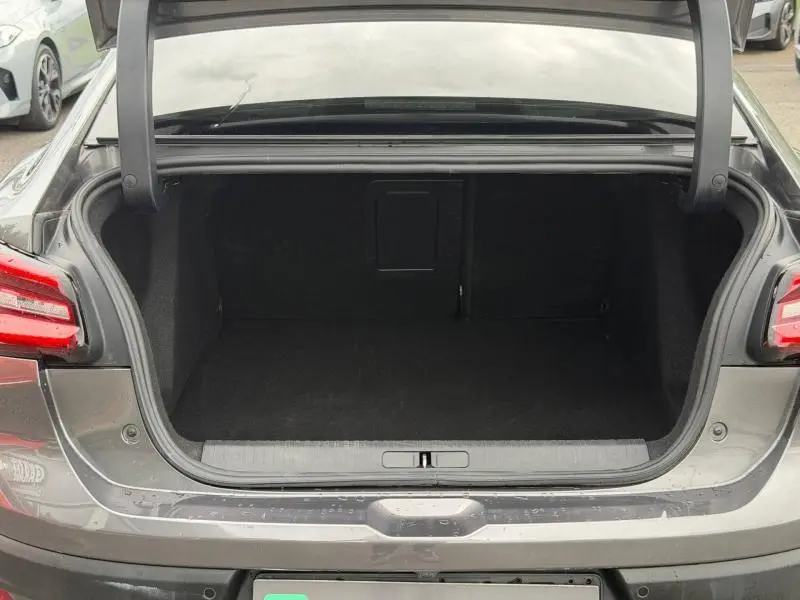 Coffre ouvert vu de l'arrière du Citroën C4 X 2024 gris Platinium, espace de chargement vide et bien fini.