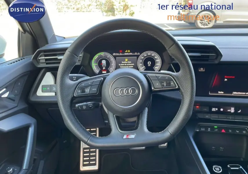 Vue intérieure centrée sur le volant cuir perforé de l'Audi A3 Sportback 40 TFSIe avec tableau de bord digital et console moderne.