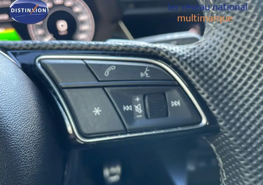 Gros plan sur les commandes du volant côté gauche de l’Audi A3 Sportback blanc Ibis 2025 hybride rechargeable.