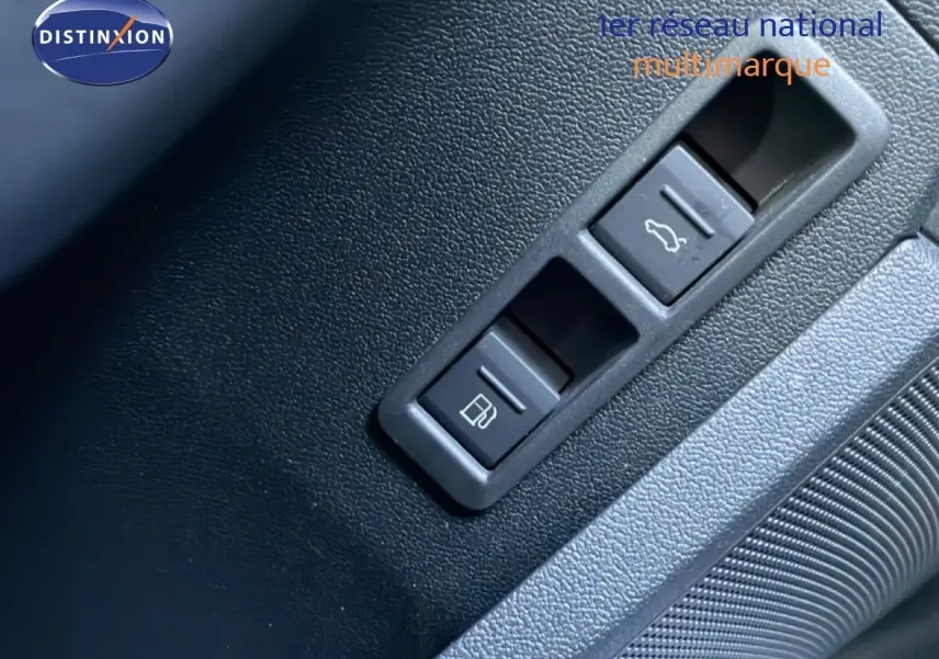 Gros plan sur les commandes d'ouverture de trappe à carburant et coffre dans l'habitacle noir d'une Audi A3 Sportback blanche.