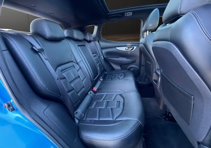 Vue intérieure côté droit des sièges arrière en cuir noir du Nissan Qashqai bleu 2018, avec appuie-têtes et ceintures visibles.