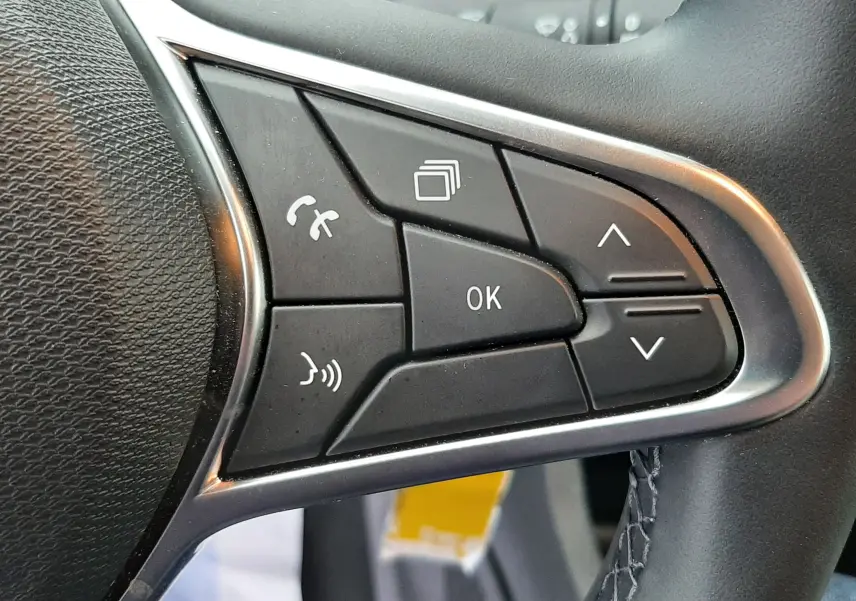 Gros plan sur les commandes multifonctions côté droit du volant en cuir noir de la Renault Clio V gris schiste.