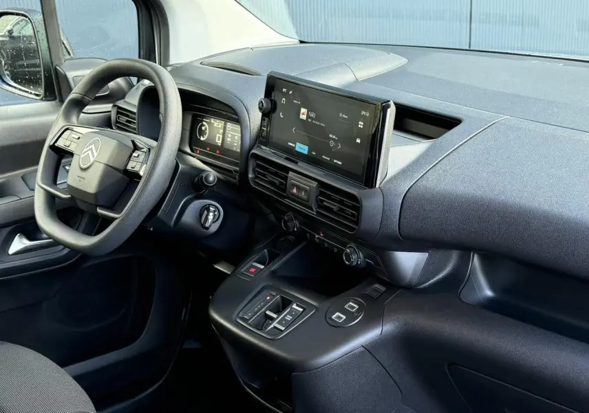 Intérieur côté conducteur du Citroën Berlingo 2025, tableau de bord noir avec écran tactile central et volant multifonctions.