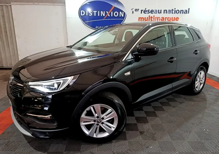 Opel Grandland X noir vue 3/4 avant droit dans un showroom avec jantes alliage et phares LED allumés.
