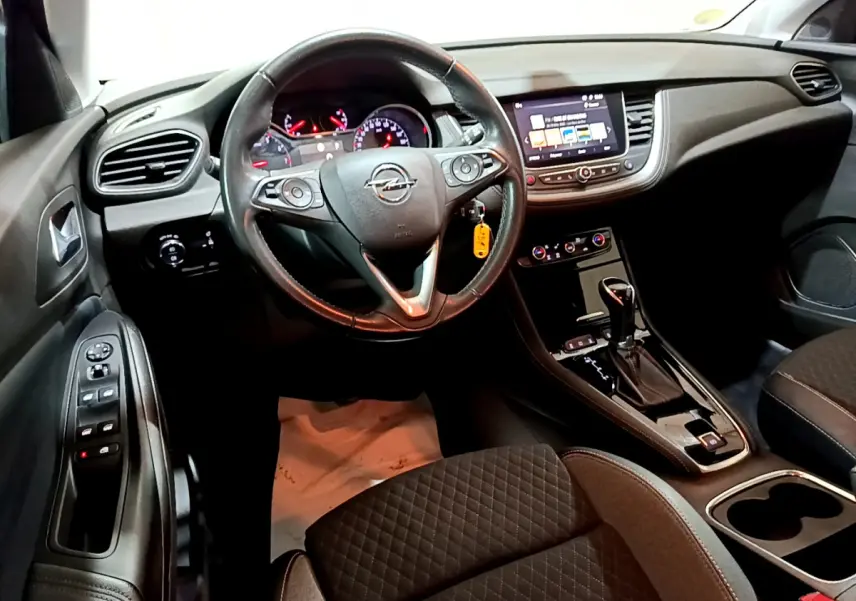 Intérieur noir de l'Opel Grandland X 2021, vue du poste de conduite avec volant cuir et écran tactile central.