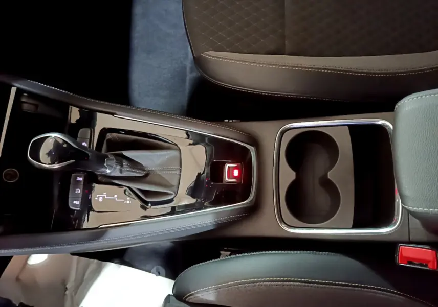Vue plongeante sur la console centrale noire de l'Opel Grandland X 2021 avec levier de vitesse automatique et porte-gobelets.