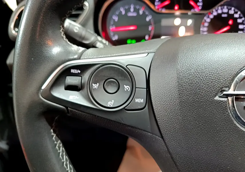 Gros plan sur le volant cuir noir de l'Opel Grandland X 2021 avec commandes de régulateur de vitesse et tableau de bord lumineux.