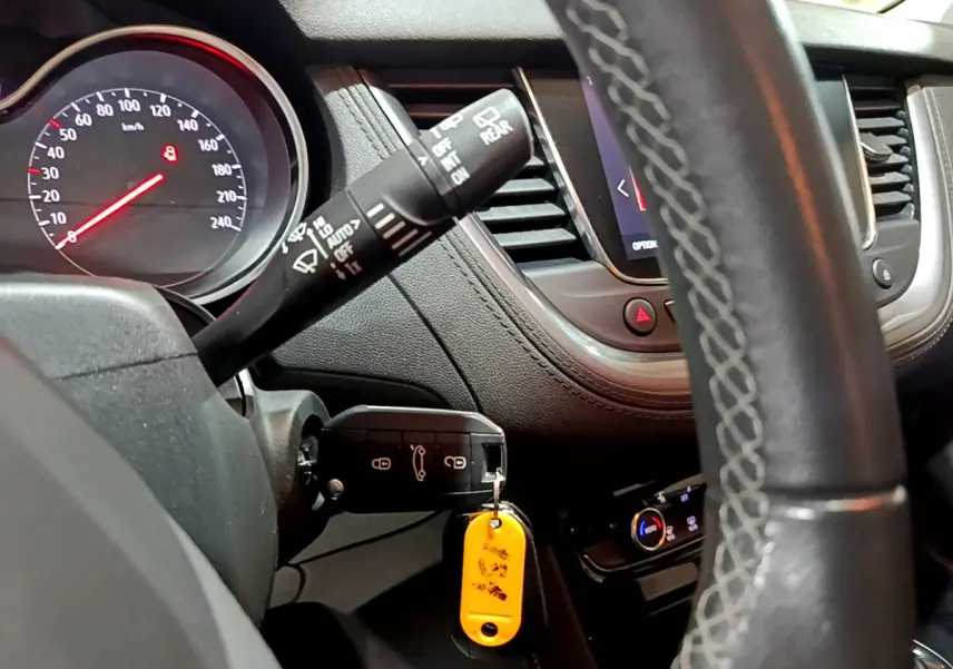 Vue rapprochée du tableau de bord noir de l'Opel Grandland X 2021, volant cuir et clé avec porte-clés jaune visible.