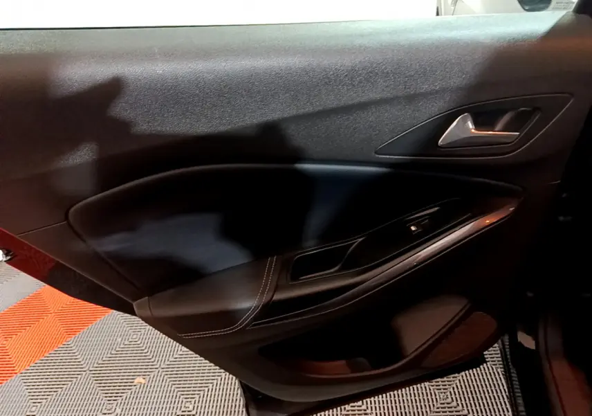 Gros plan sur la porte intérieure côté gauche de l’Opel Grandland X noir, avec poignée argentée et commande de vitre.