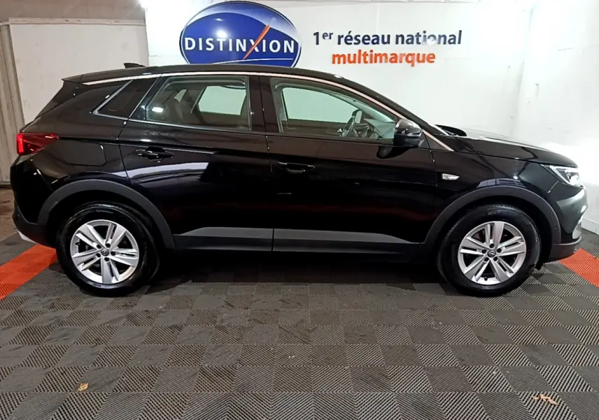 Opel Grandland X noir vue de profil côté gauche, dans un showroom avec logo Distinxion en arrière-plan.