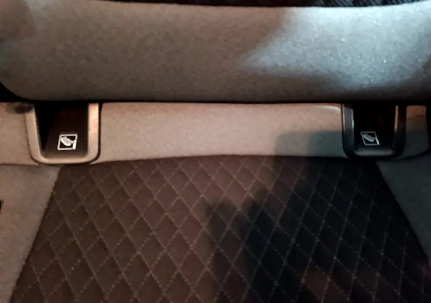 Gros plan sur les commandes de rabattement des sièges arrière du coffre du SUV Opel Grandland X noir.