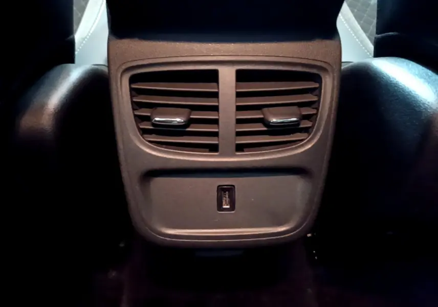 Prise USB et aérateurs arrière noirs du Opel Grandland X 1.5 Diesel 130 Elegance Business Auto, vue centrée du bas des sièges avant.