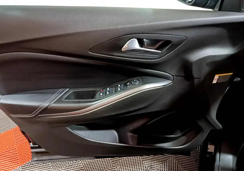 Gros plan sur la porte intérieure côté conducteur de l'Opel Grandland X noir, avec commandes électriques et poignée argentée.