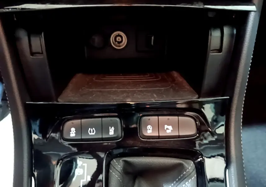 Gros plan sur la console centrale noire de l'Opel Grandland X 2021 avec boutons d'aide au stationnement et frein électrique.