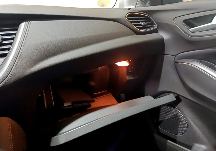Intérieur de l'Opel Grandland X 2021, vue côté passager sur boîte à gants ouverte avec éclairage intérieur chaud.