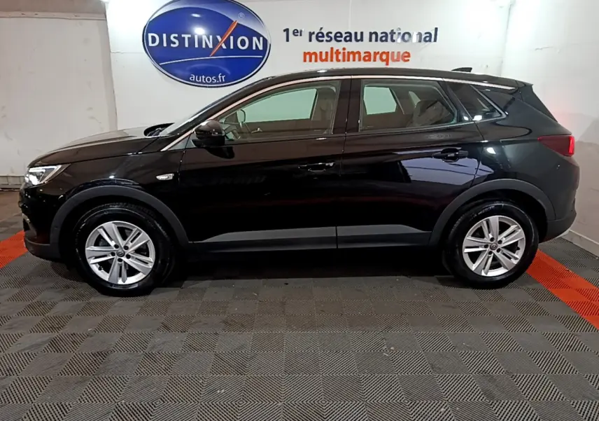 Opel Grandland X noir vu de profil côté gauche dans un garage avec logo Distinxion en arrière-plan.
