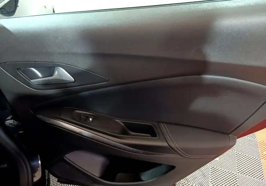 Vue intérieure du panneau de porte côté gauche noir de l'Opel Grandland X 2021 avec poignée argentée et commande de vitre.