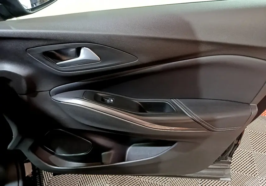 Gros plan sur la porte côté gauche noire de l'Opel Grandland X avec poignée argentée et commande de vitre.