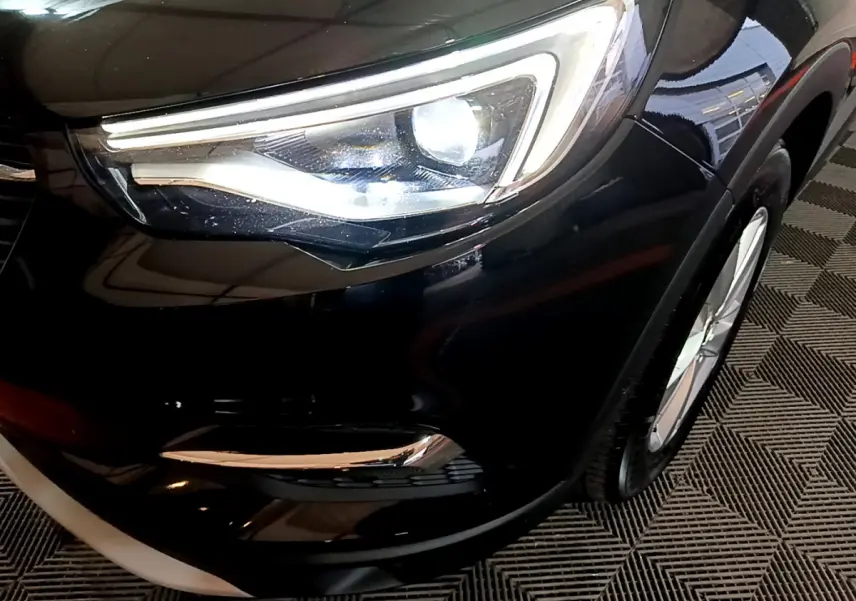 Gros plan sur le phare avant droit du SUV Opel Grandland X noir, mettant en valeur son design LED moderne.