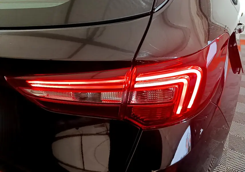 Gros plan sur le feu arrière droit rouge allumé d’un Opel Grandland X noir, reflétant l’environnement intérieur.