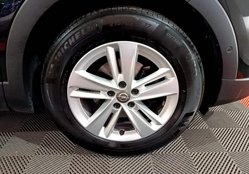 Gros plan sur la roue avant gauche noire de l'Opel Grandland X Diesel 2021 avec passage de roue gris anthracite.