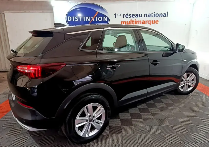 Opel Grandland X noir vue 3/4 arrière droit en intérieur, avec jantes alliage et feux arrière LED allumés.